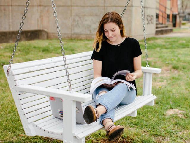 Female student reading on porch swing